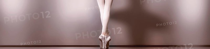 A panoramic view from the back of the beautiful legs and feet on tiptoes dressed in pointe shoes of a young ballerina