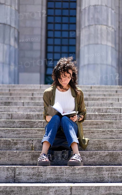 Vertical shot of thoughtful woman sketching on the steps of her college