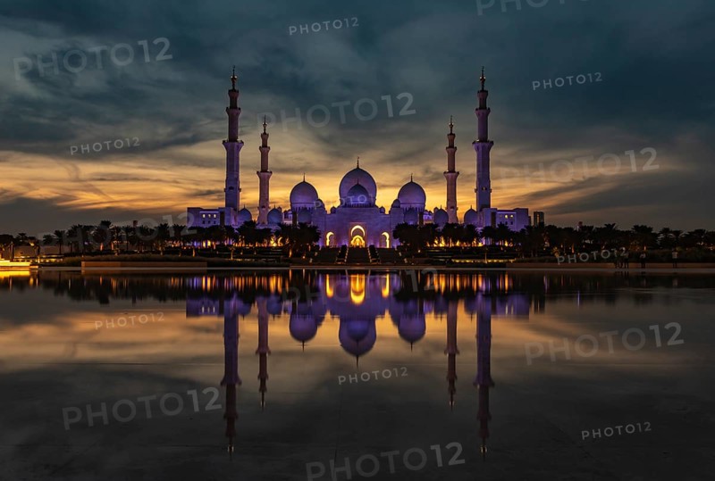 A picture of the Sheikh Zayed Grand Mosque reflected on the Oasis of Dignity pool, at sunset