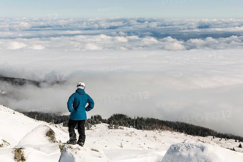 Freestyle skier is looking from the top of a peak of Vitosha mountain covored in clouds. He is participating in an freestyle competition of skiers and snowboarders