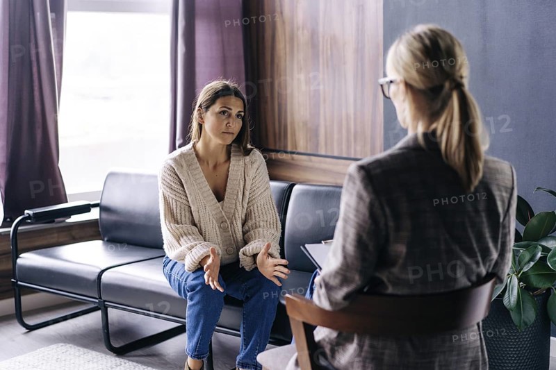 Eine junge Frau spricht in einem Gespräch mit einem professionellen Psychologen über ihre Probleme. Eine moderne Frau entscheidet in einem vertraulichen Gespräch mit einem professionellen Berater, was zu tun ist