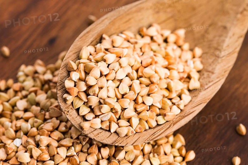 Buckwheat with a spoon on a wooden boards background