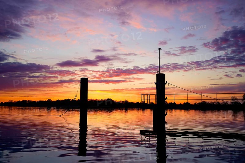 Bollard on the water in a pink morning sky with atmospheric reflection at dusk, An der Kaje / Weser, 26919 Brake-Germany