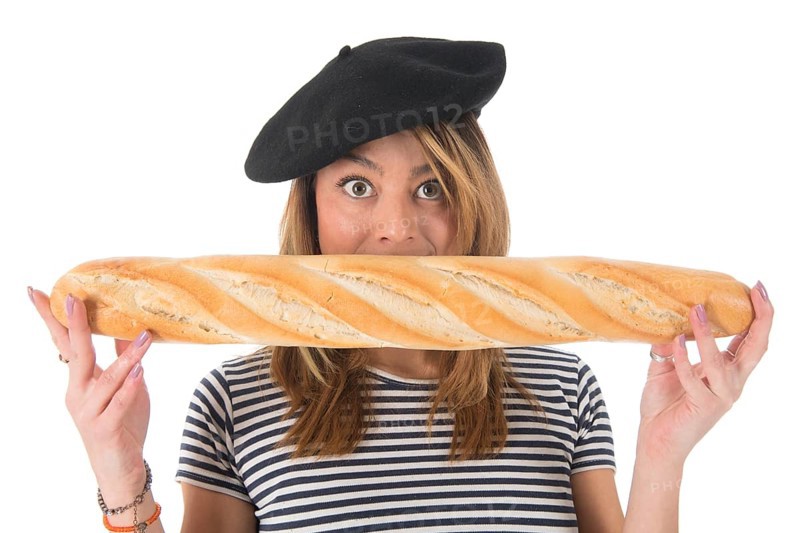 Young French girl with typical French barret and striped shirt eating bread isolated over white background