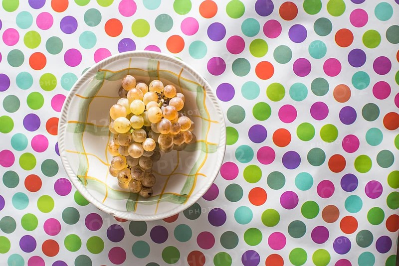 Plate with grape on colorful background