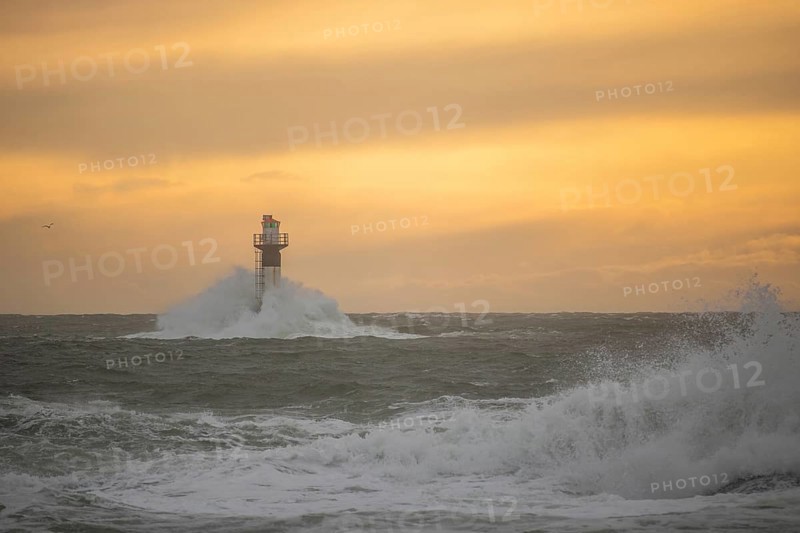 A lighthouse stands in the storm. Wild sea in the evening. Sunset on a coast with many rocks in the North Sea. Seascape in Sweden, Scandinavia