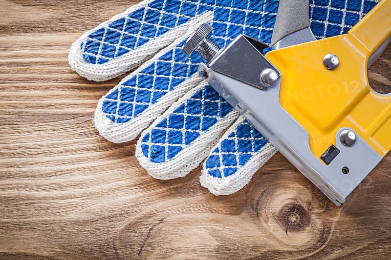 Construction stapler safety working gloves on wood board directly above