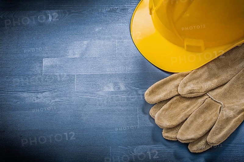 Protective gloves building helmet on wooden board construction concept