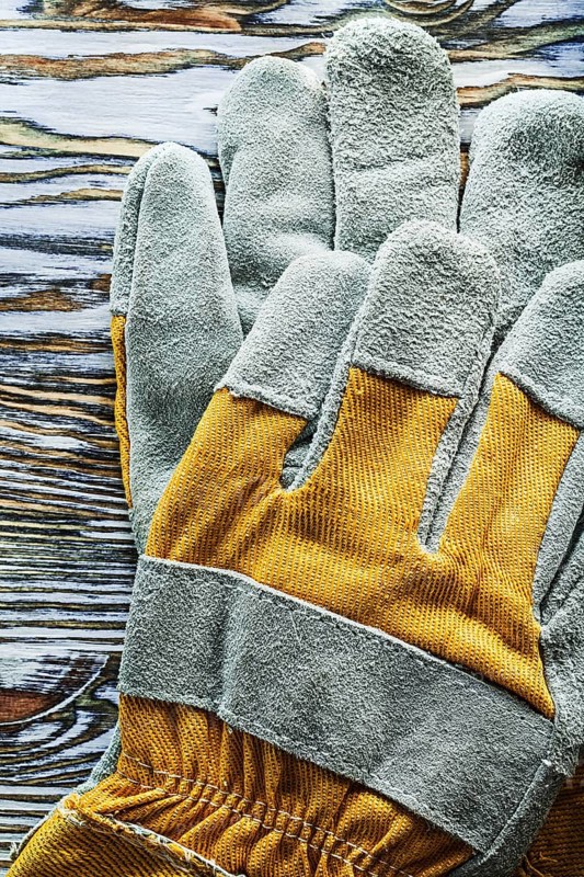 Protective gloves on wooden board top view