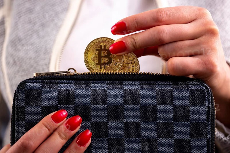 Virtual cryptocurrency money Bitcoin golden coins in the left hand of a woman with red nail polish and a purse. The future of money