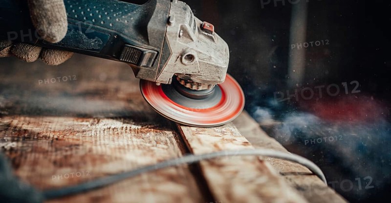 A grinder on wood creating dust and spirals, focused and dynamic