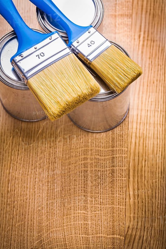 Vertical view organized copyspace two paint brushes on three cans and wooden board