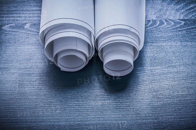 White rolled up blueprints on blue painted board