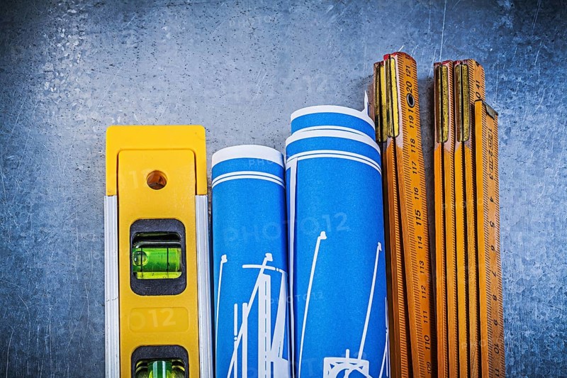 Wooden meter blue construction drawings level on metallic background