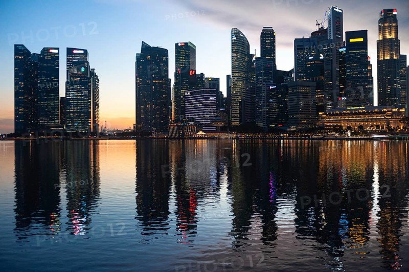 02.12.2020, Singapore, Republic of Singapore, Asia, View over Marina Bay to the illuminated business district with its modern skyscrapers in the evening light during the global corona pandemic
