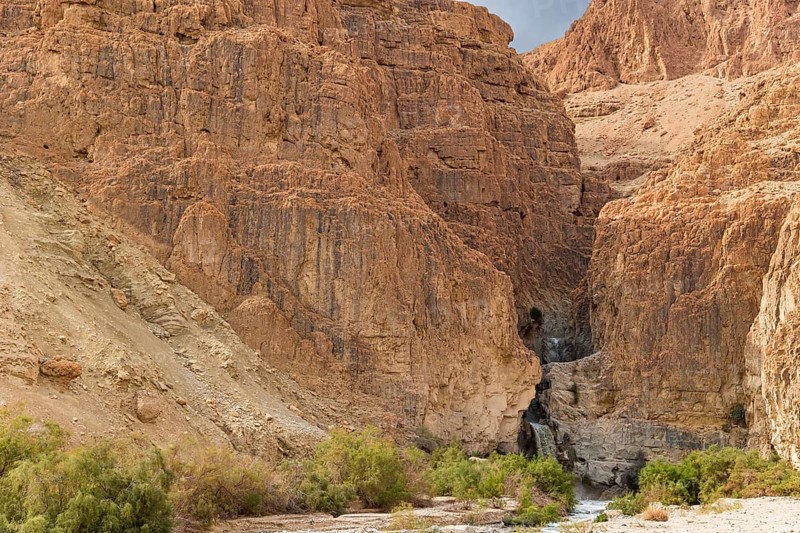 Cascading waterfall in a narrow gorge. The Judean Desert around the Dead Sea after heavy winter rains. Israel, winter cloudy day