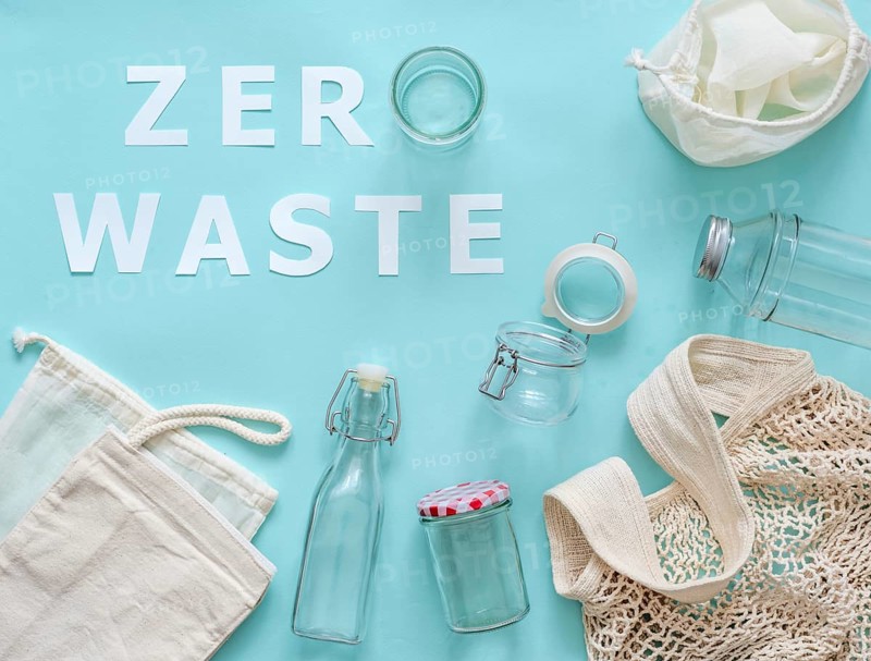 Zero waste concept. Textile eco bags, glass jar and bottle on blue background with Zero Waste white paper text. Eco friendly and reuse concept. Top view or flat lay