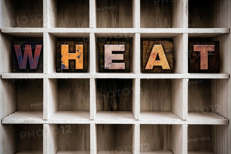 The word WHEAT written in vintage ink stained wooden letterpress type in a partitioned printer's drawer