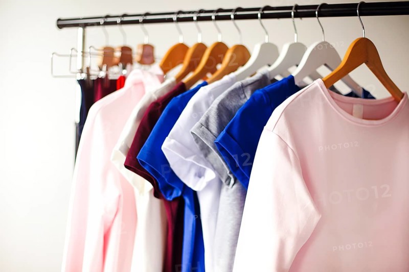 Rack with various feminine shirts placed in minimalist style room with white walls