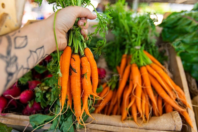 First person perspective as a shopper buys locally produced organic carrots at a market stall during a street fair with copy space on the right