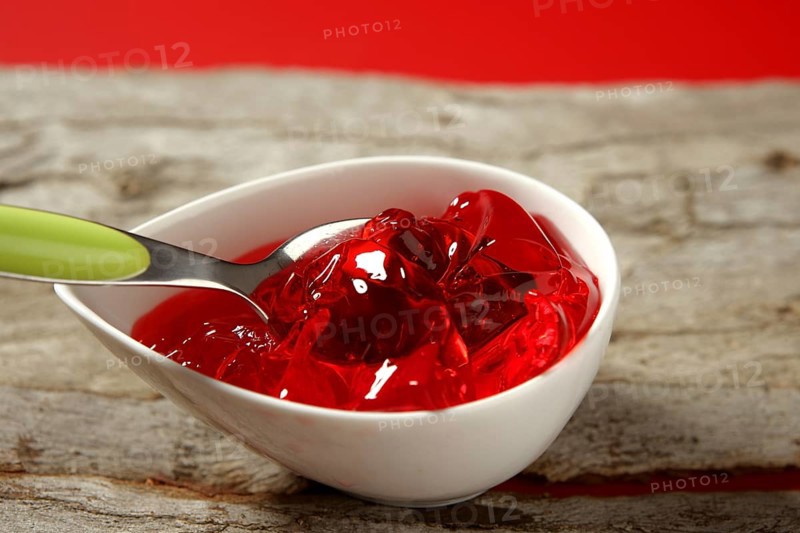 Bowl full of strawberry red sweet jelly and green spoon