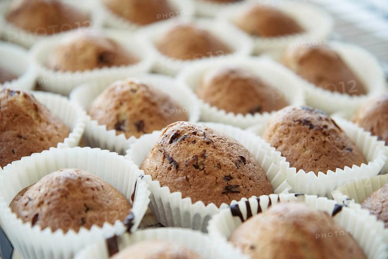 Homemade Muffins with Chocolate Chips on a Oven Grill over a Wooden Table, in a shallow depth of field. Homemade pastries