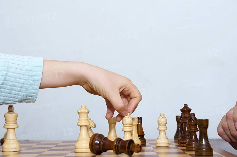 Close-up of a child's hands playing chess with a white background and copy space