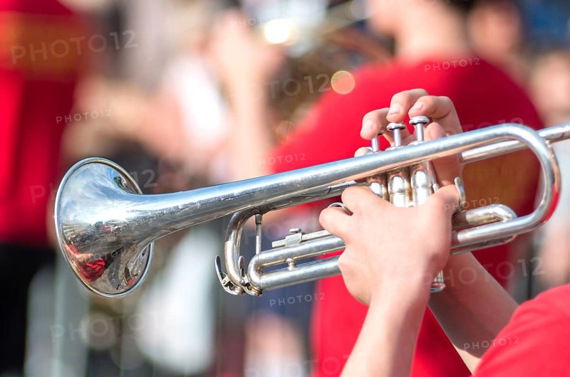 A jazz trumpeter plays of his trumpet in the brass band during a carnival live event. Blurry close up plan of trumpeter plays jazz.