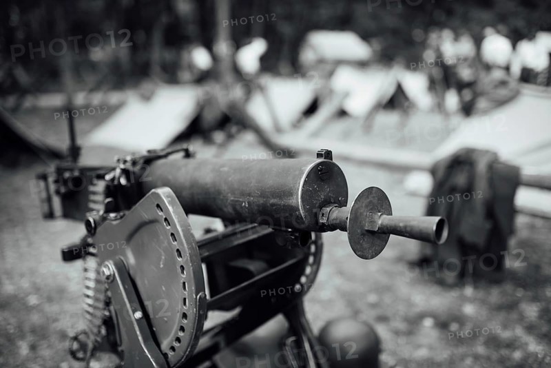 A heavy machine gun from I Word War with a military camp in the background