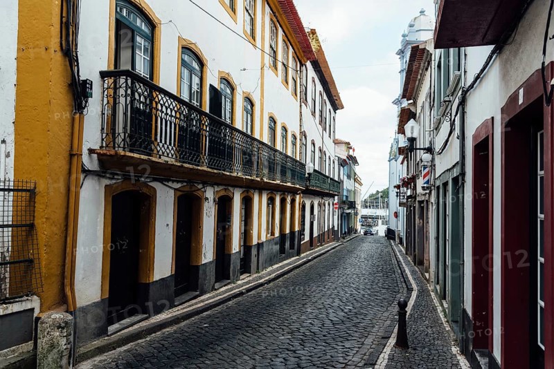 Angra do Heroismo, Portugal, July 1, 2022: Street with Traditional colonial houses painted in vibrant colors in the old town. Terceira Island, Azores
