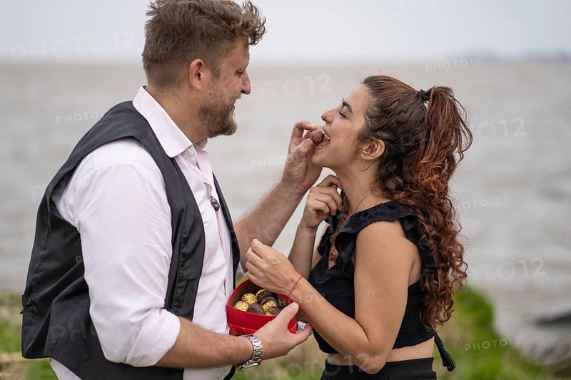 Man giving his girlfriend chocolate in the mouth on a beach