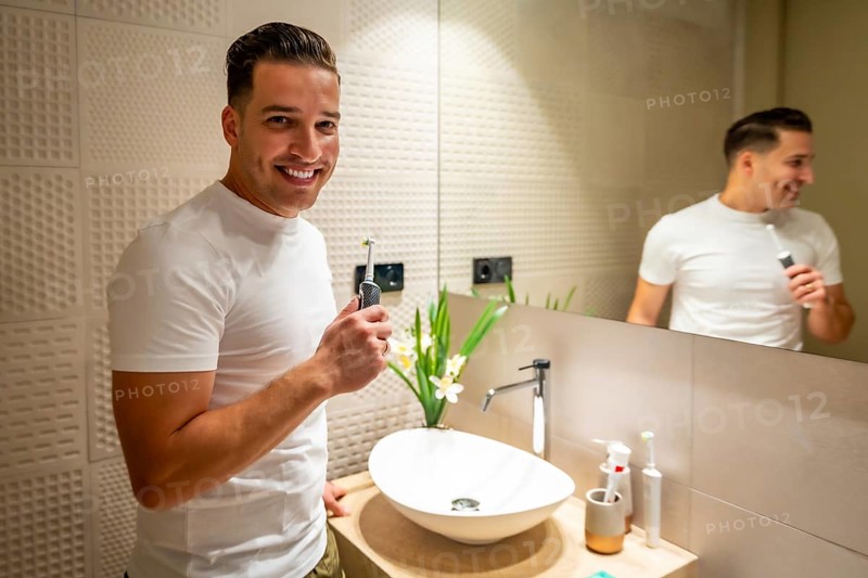 Man smiling at camera after cleaning his teeth in the bathroom