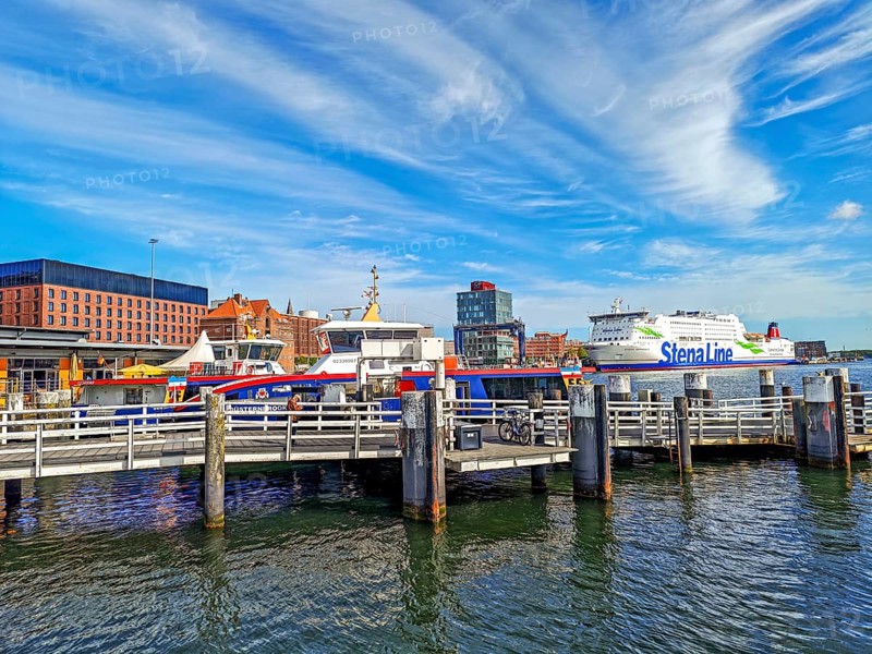 Maritime atmosphere in the harbour at the end of the Kiel Fjord, jetty, liner ships, Sweden ferry of the Stena Line at the quay, seafaring, glass building and brick architecture, dolphins, sunshine, cirrocumulus clouds, blue sky, Baltic Sea, Kiel, Schleswig-Holstein, Germany
