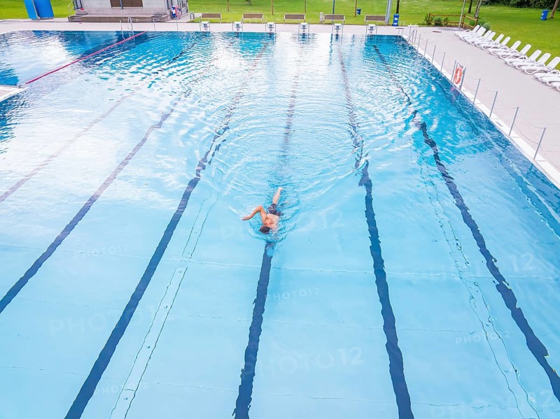 A swimmer moves in an almost empty swimming pool with clear lanes, Calw outdoor pool, Black Forest, Germany