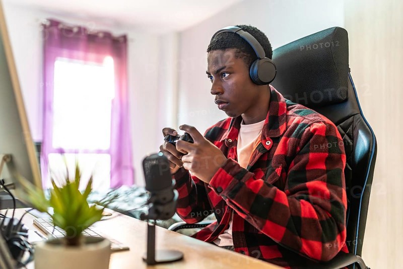 Young man focusing intently on playing video games while streaming live from a well equipped home setup, engaging with an online audience