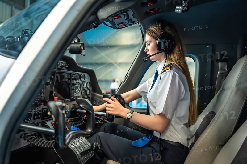Confident female pilot using electronic flight bag while sitting in cockpit of small airplane preparing for flight