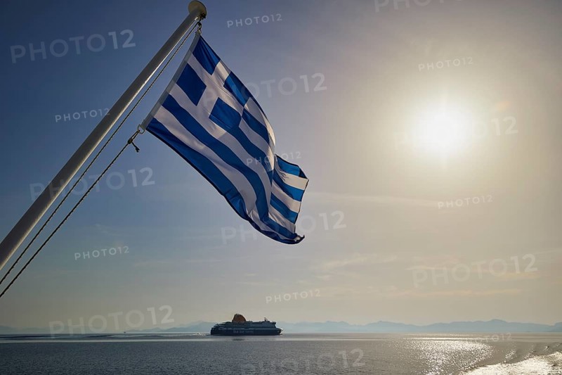 Greek flag waving, with a ship in the background and sunny sky, crossing Rhodes to Symi, ferry, Symi, Dodecanese, Greek Islands, Greece