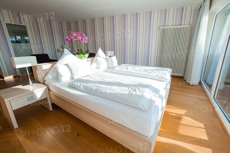 Bright bedroom with double bed, wooden floor and purple striped walls, Hotel Krone Lamm, Zavelstein, Black Forest, Germany