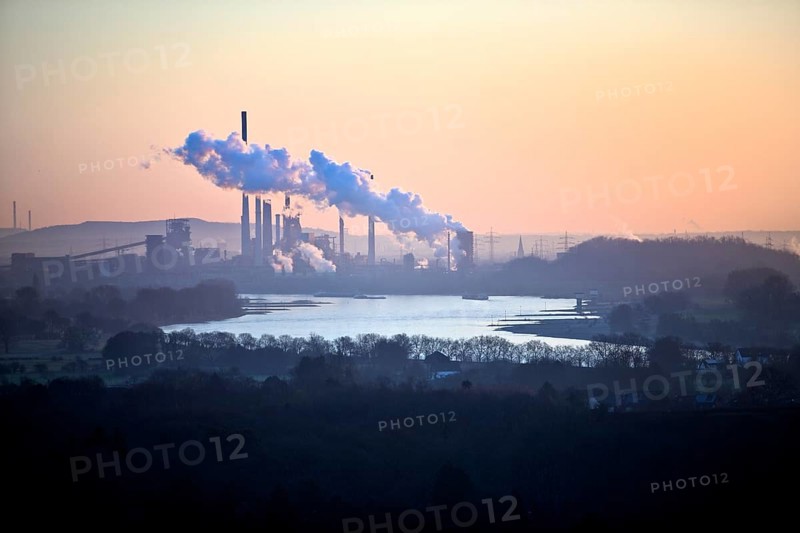 View in front of sunrise from the Rheinpreussen spoil tip onto the Rhine in Duisburg with the Thyssen Krupp plant in Bruckhausen, Germany