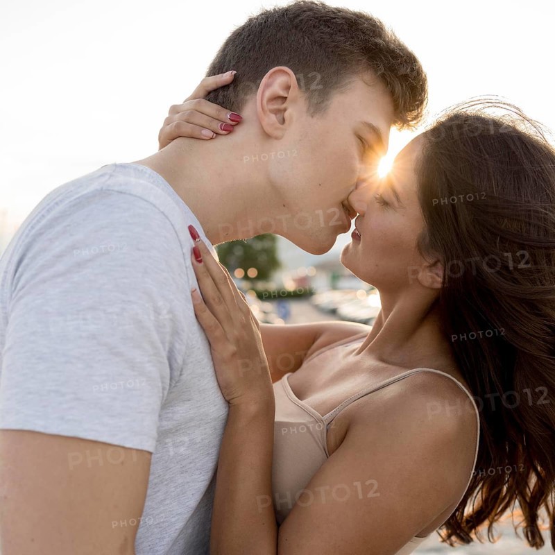Side view couple kissing with sun peeking them