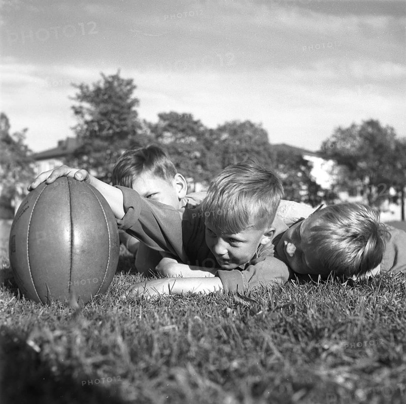 Rugby 1940. Three young rugby players lying in the grass on the rugby field, one holding the rugby ball. The rugby ball has an oval shape, four panels and a weight of about 400 grams. 1942. Kristoffersson ref A56-5