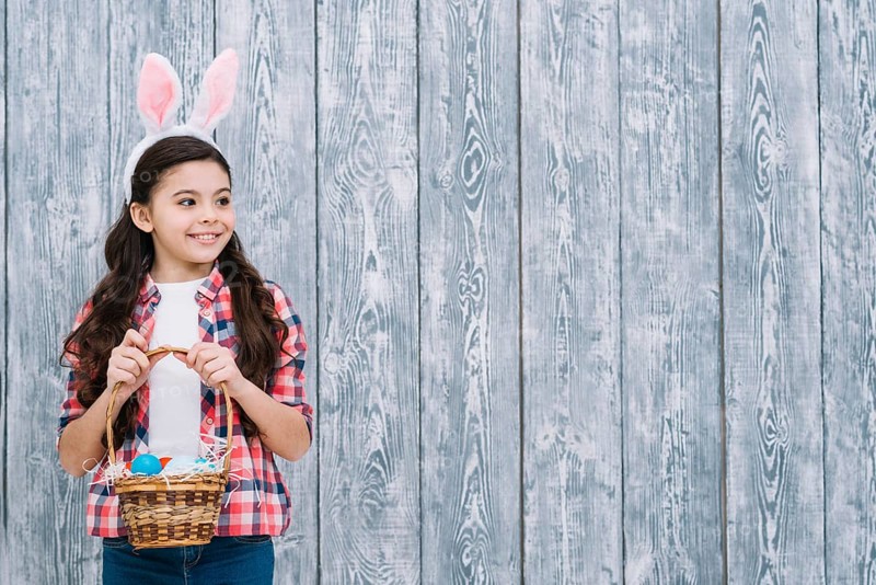Portrait girl with bunny ears holding easter eggs basket looking away
