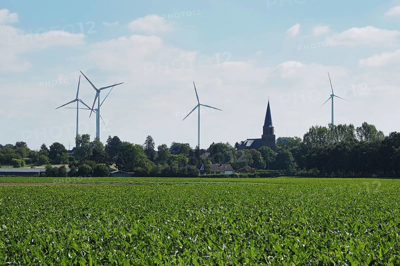Wind turbines for power generation on the edge of the Garzweiler open-cast lignite mine, with a church tower behind, Rhenish lignite mining area, Germany