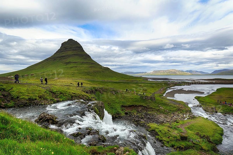 Kirkjufell mountain, film set, hikers, tourists at Kirkjufellfoss waterfall, Kirkjufellsa river, coastline at Grundarfjördur, Snæfellsnes peninsula, Vesturland, Iceland