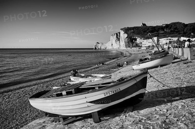 Rowing boat, boats lying on the beach, pebble beach, rock arch Falaise or Porte d'Amont, church Chapelle Notre Dame de la Garde, Étretat, sea, steep coast, cliffs, chalk cliffs, alabaster coast, La Côte d'Albâtre, black and white, Normandy, Seine-Maritime, France