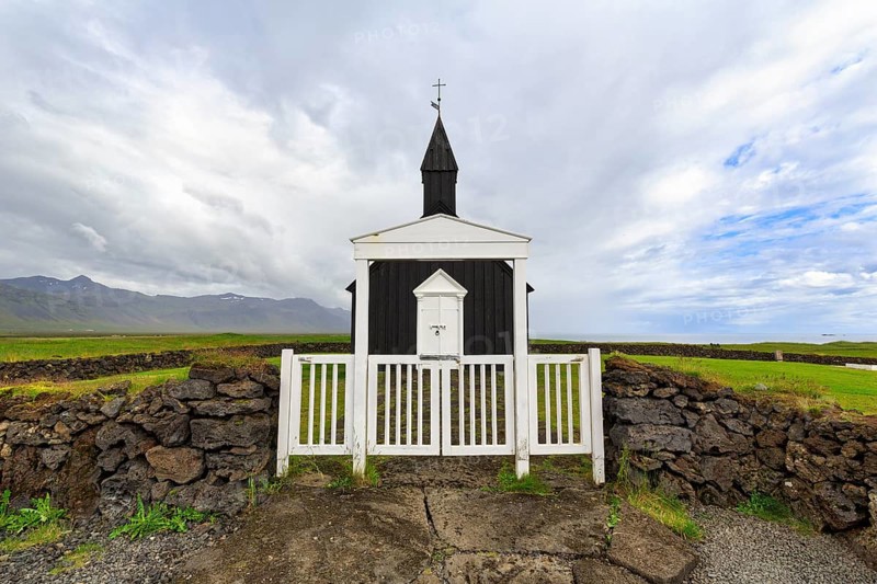 Traditional black church with white wooden door and stone wall, wooden church Budakirkja, Búðir, Budir, Snaefellsnes Peninsula, Iceland