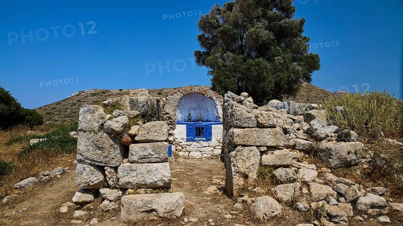 Stone chapel with blue façade amidst ancient ruins, embedded in lush vegetation, Artemis Temple, Artemis, Diana, goddess of the hunt, altar. Church, tower, near the airport in the north of the island, Leros, Dodecanese, Greek Islands, Greece