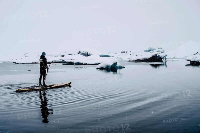 Man stand up paddling, snowfall, glacial lake Jökulsarlon at Vatnajökull, Iceland* Man stand up paddling on glacial lake Jokulsarlonat Vatnajokul, snowfall, Iceland