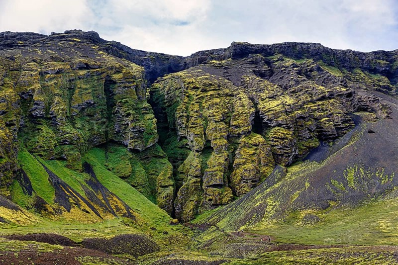 Moss-covered rock formation with entrance to the mystical lava cave, Sönghellir lava tube, Cave of Songs, Arnarstapi, Snaefellsjökull National Park, Snaefellsnes Peninsula, West Iceland, Iceland