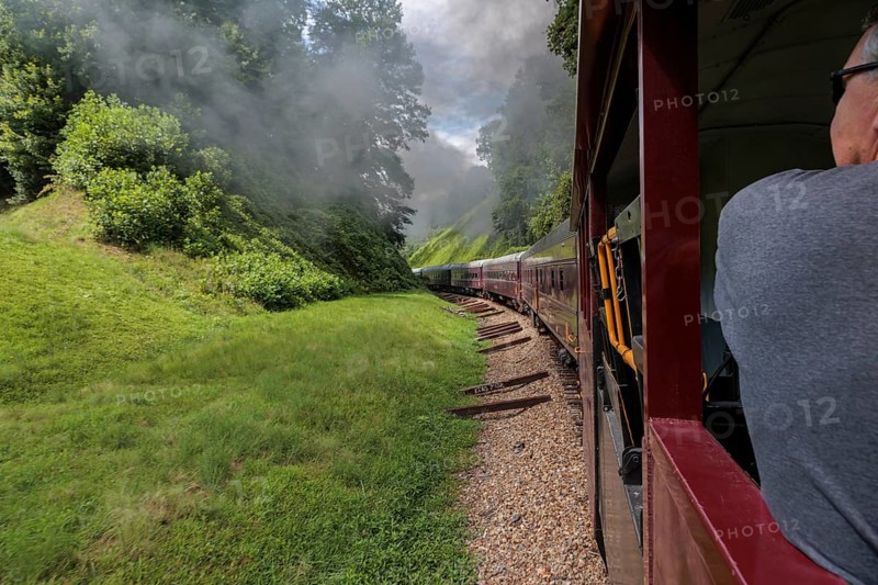 Steam from the Great Smoky Mountains Railroad hangs in the air as the train rounds a curve through the mountains of North Carolina